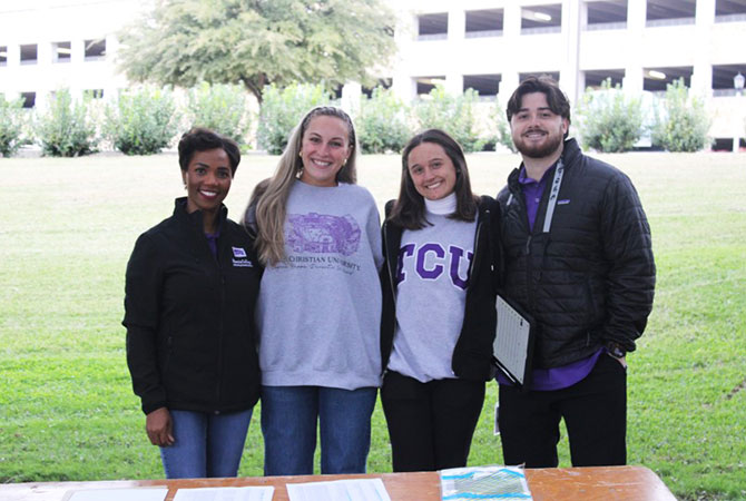 faculty member and students at an outdoor tabling event