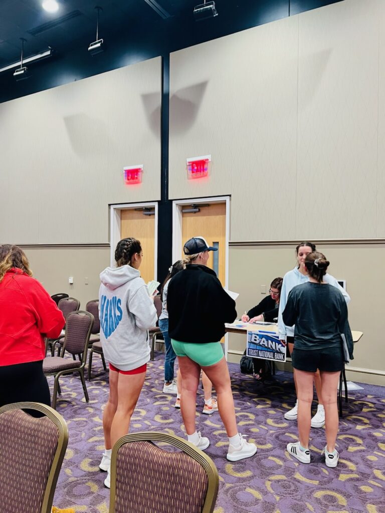 Poverty simulation participants wait in line at the “bank” to cash their paychecks or apply for bank loans.