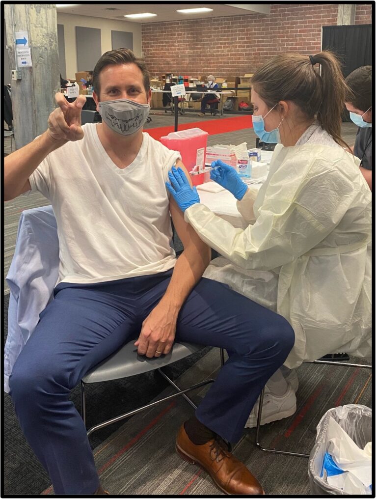 Harris College Dean, Chris Watts, get his flu vaccine by TCU nursing student.