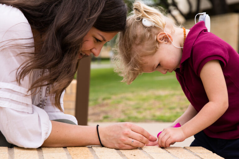 A speech-language pathology graduate student provides speech therapy to a child with a cochlear implant