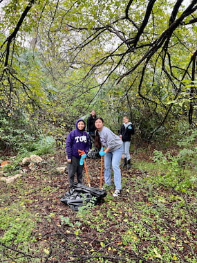 TCU students posing with trash pickers and trash bags at Glenwood Park