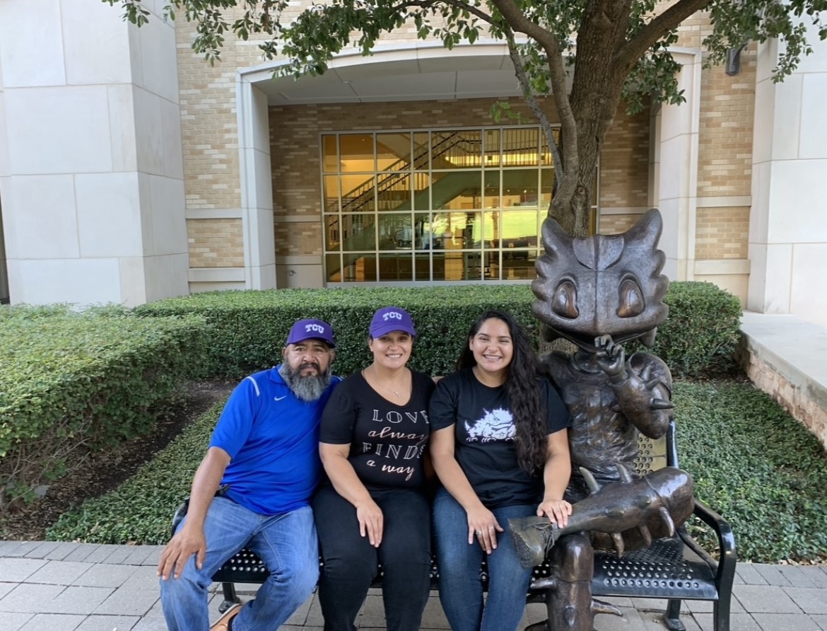 Elena with her parents sitting on a bench next to supper frog