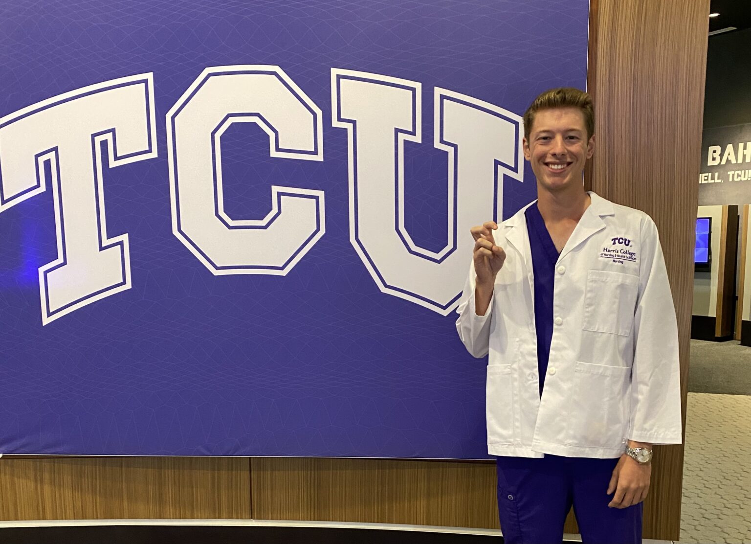 Garrett Harvill posing in front of TCU banner